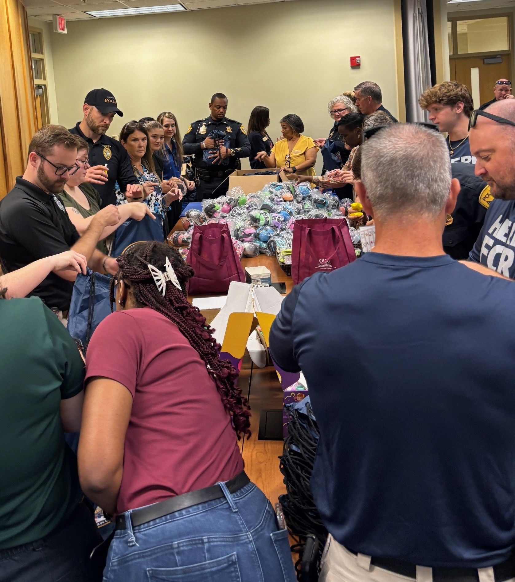 Volunteers move down opposite sides of a long table, stuffing bags with sensory comfort items.