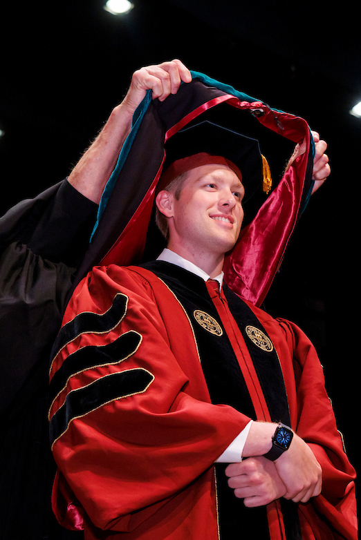 Ben Linkous is hooded by Pensacola Regional Campus Dean, Dr. Paul McLeod.