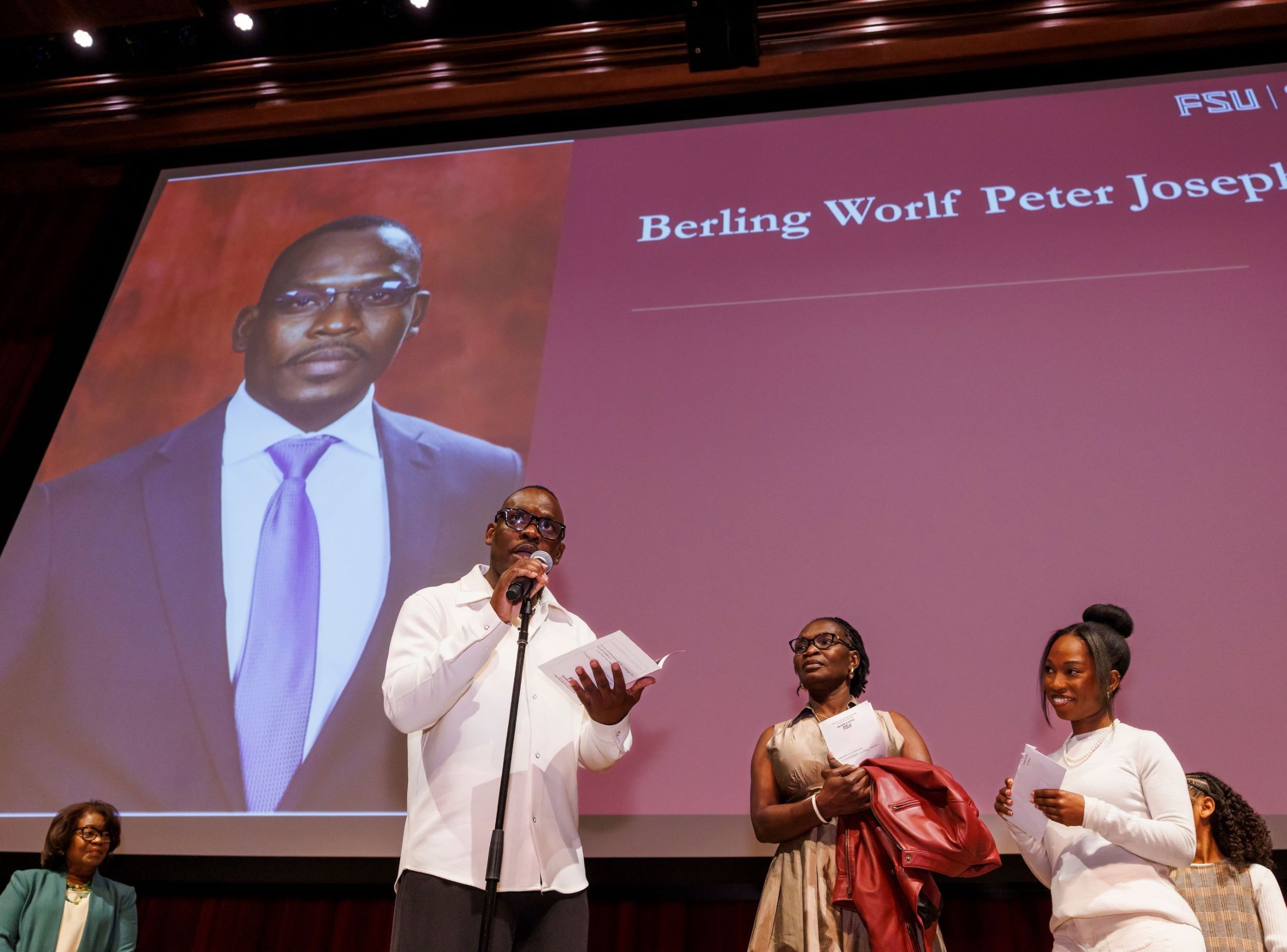 Berling Joseph announces his match on the stage at Ruby Diamond Concert Hall, as his family and Fort Pierce Regional Campus Dean Juliette Lomax-Homier, M.D. watch.