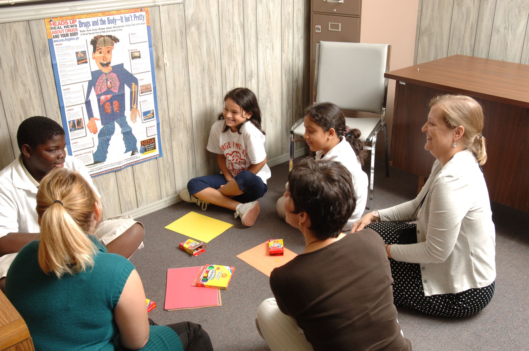 Students and educators sit in a circle learning about good health habits.