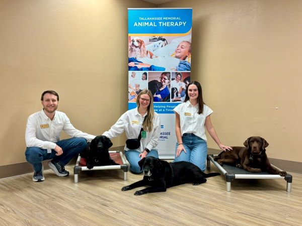 Students, Tyler Odum, Rachel Bielling, and Abigail Watson posing with three dogs.