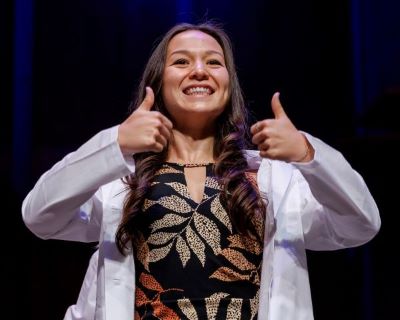 Liana Patterson gives two thumbs up to the audience after getting her white coat.
