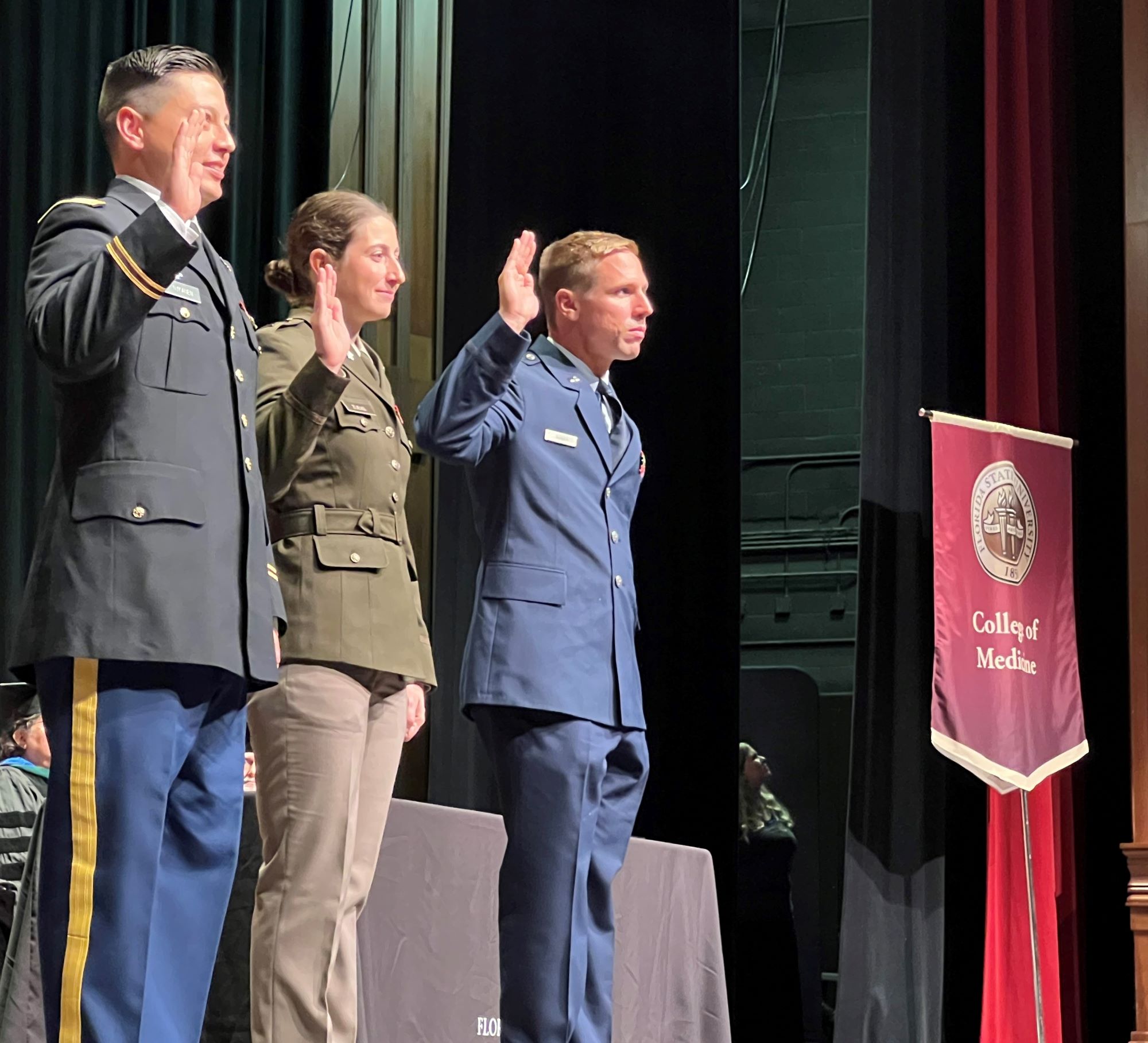 Dr. Jordin Giles Zuelke among the three Dr. Brian Nykanen, Dr. Jordin Giles Zuelke and Dr. Eric Minnix raise their right hands to reaffirm their military oaths of office following their promotions to captain, Nykanen and Zuelke in the Army and Minnix in the Air Force. 