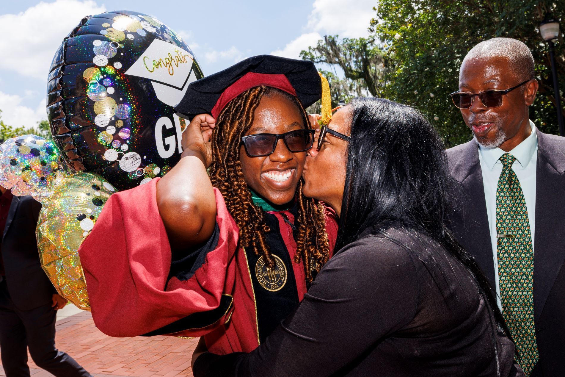 Sharon Baugh kisses the cheek of her daughter, Dr. Shellon Baugh, while dad Helan Baugh looks on proudly.