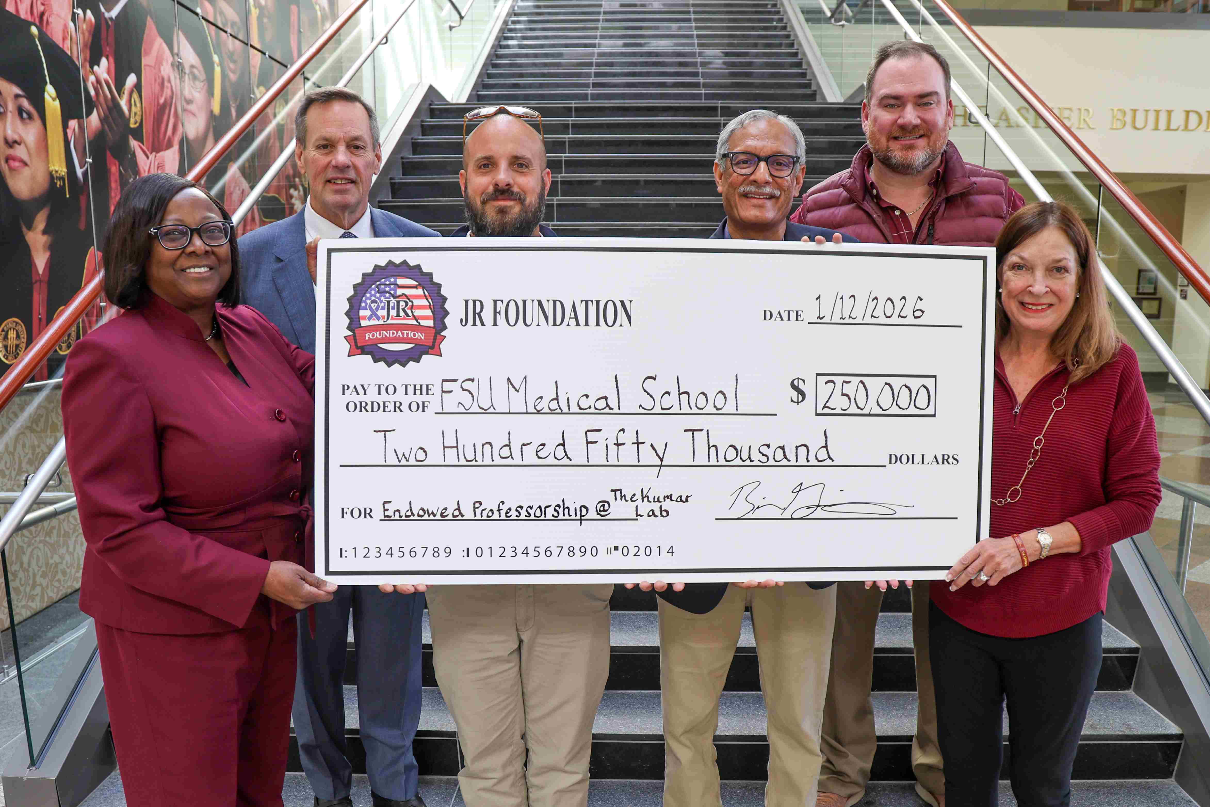 Posed with a giant check for $250,000 are, from left, Dean Alma Littles, M.D., Chris and Chase Kraft, Sanjay Kumar, Bill Gilbert and Kellie Kraft.