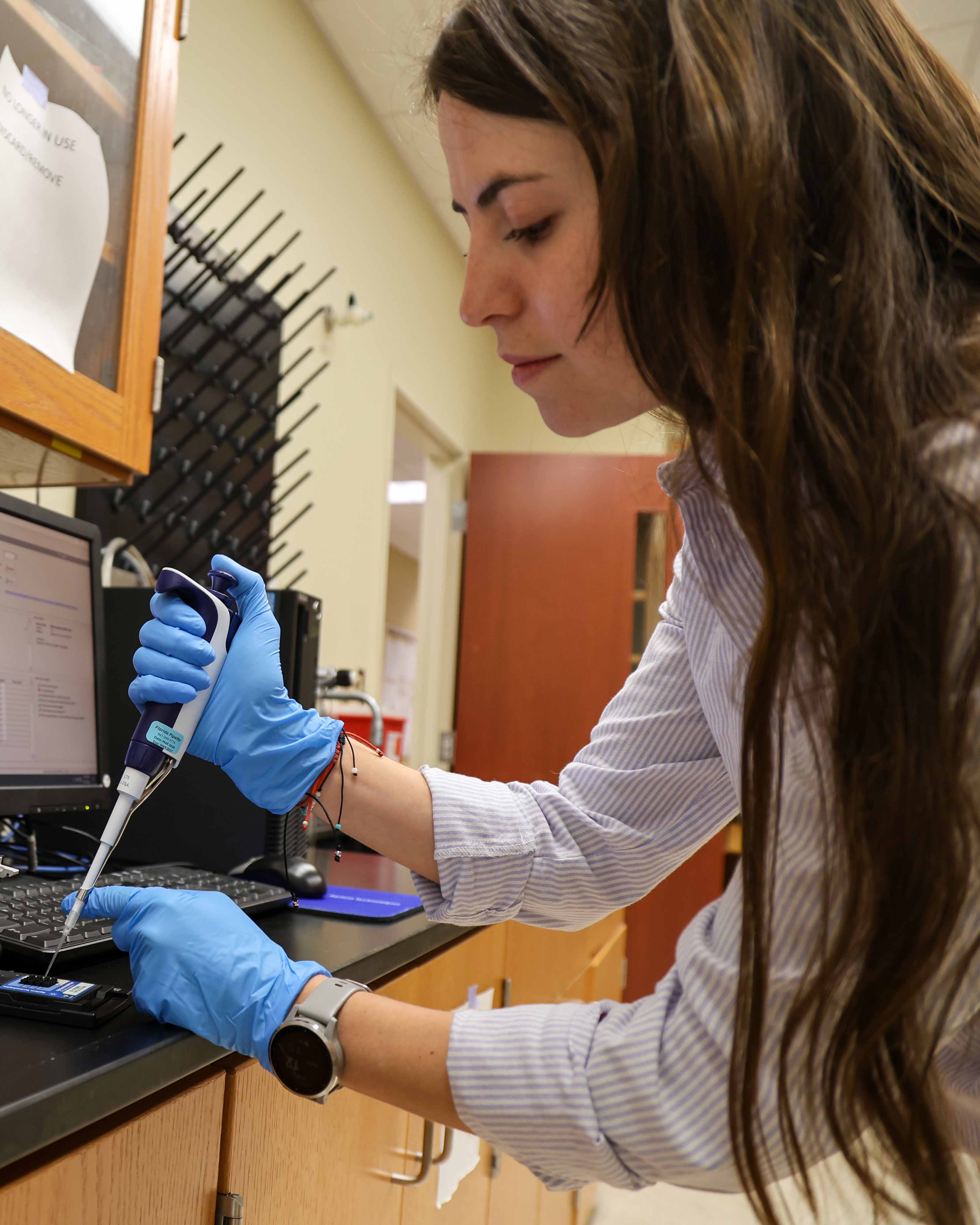 Pilar Toledo, M.D. pipetting at the bench Wang's Lab in FSU Biomedical Sciences.