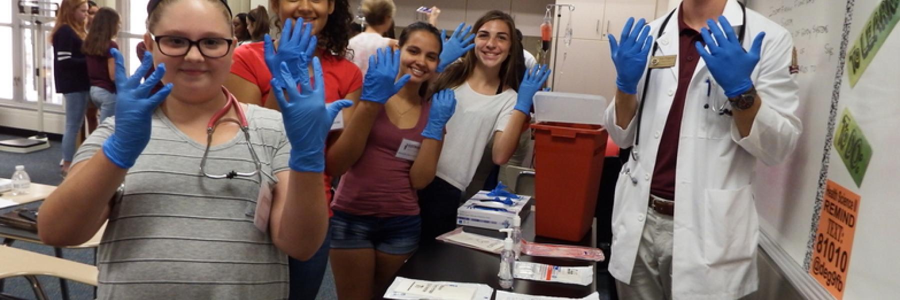SSTRIDE students holding up hands wearing latex gloves