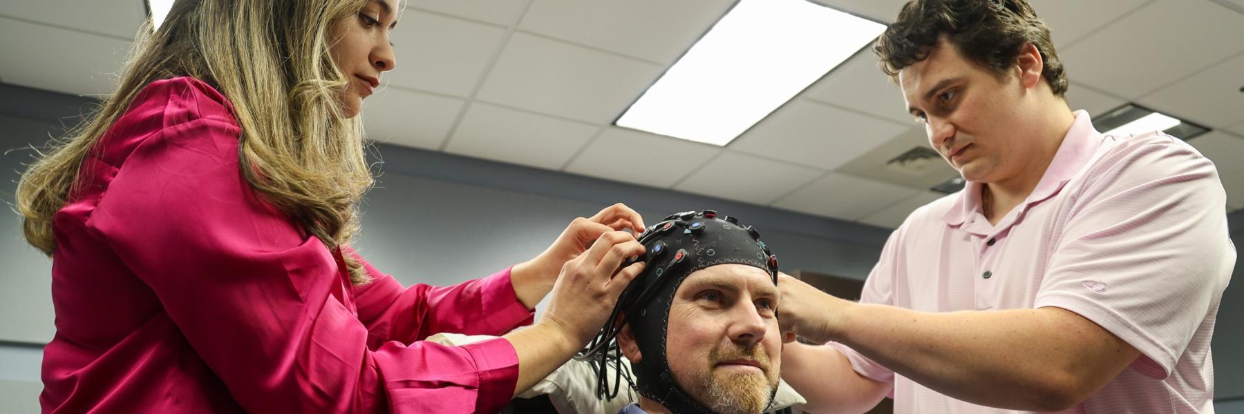 image of staff putting the fNIRS cap on a fake participant