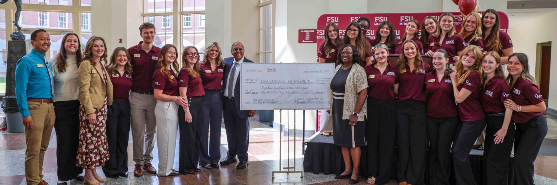 College of Medicine Dean Alma B. Littles, M.D., standing to the right of a ceremonial check, is joined by Dr. Rashmin Savani, physician-in-chief at UF Health Shands Children's Hospital, standing to the left of check. To his immediate right is Grace Massari, executive director of Dance Marathon at FSU this year. Far left is Zduy Chu, Ed.D., associate vice president of FSU Student Affairs; and they are joined by this year's leadership team.