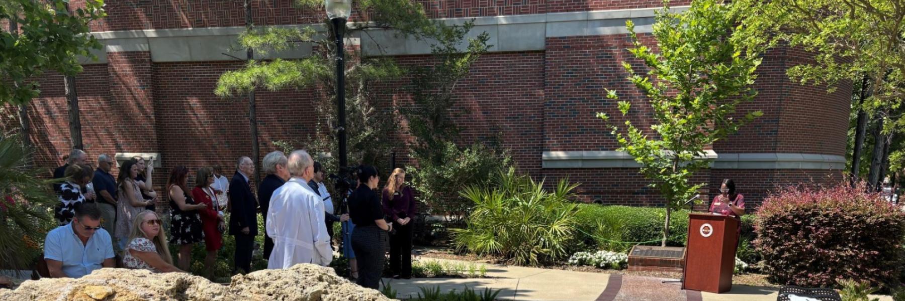 Dean Alma Littles, far right, addresses the crowd, at left, in the Chapman Wellness Garden.
