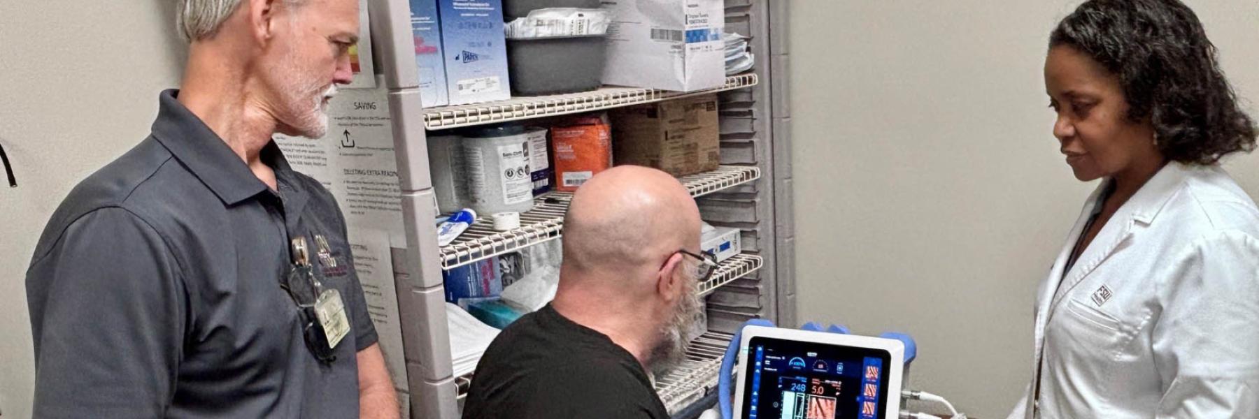 Two men and a woman stand by the liver scanner machine.