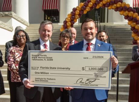 FSU President Richard McCullough and state Rep. Adam Anderson display the ceremonial check for $1 million. College of Medicine Dean Alma Littles, M.D., is at far left.