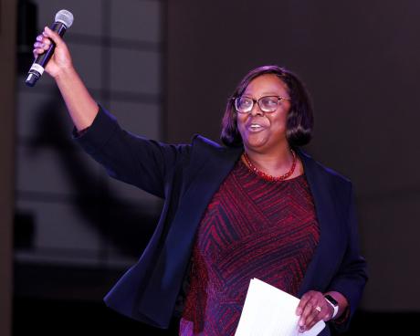 A cheering Dr. Alma B. Littles raises the microphone in tribute to Dance Marathon participants.