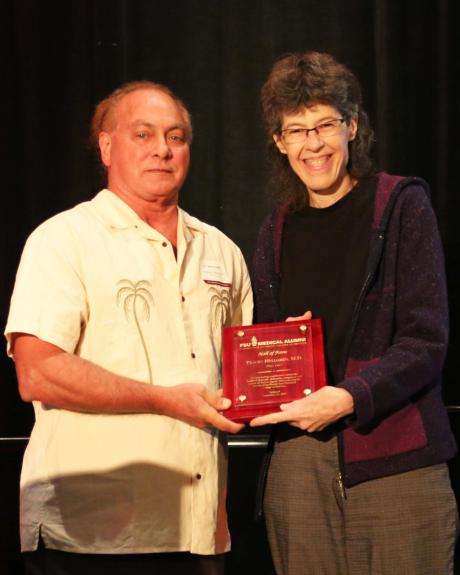 Dr. Tracey Hellgren accepts her Hall of Fame plaque from Alumni chair Dr. Ric Adkins.