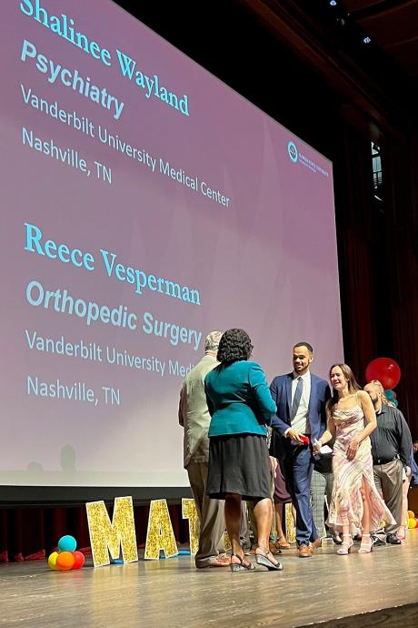 Reece Vesperman and Shalinee Wayland stop to greet Pensacola Regional Campus Dean Paul McLeod and Interim College of Medicine Dean Alma Littles before leaving the stage.