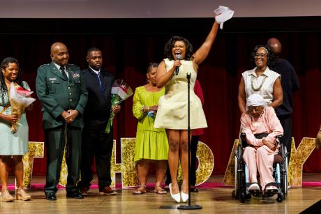 Kaleigh Wingate jumps for joy as she announces her match at Dartmouth College in psychiatry, as her extended family joins her on stage.