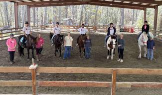 Students posing on horses with Hands and Hearts for Horses staff members.
