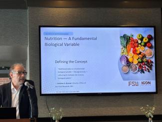 Dr. Patrick Stover stands next to a slide explaining nutrition as a fundamental biological variable.