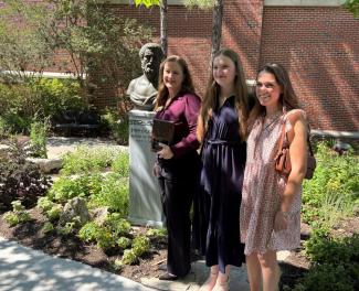 Dr. Fawn Harrison poses next to the bust of Hippocrates with her daughter and a family friend.