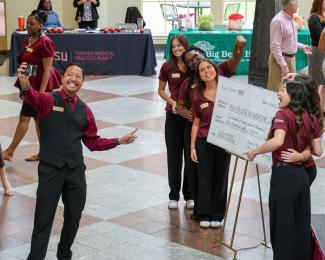 Dr. Zduy Chu, FSU Associate Vice President of Student Affairs, poses for a selfie with the Dance Marathon leadership team and the ceremonial check.