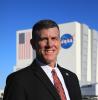 Headshot of Jeremy Graeber standing in front of a building with the NASA logo on it.